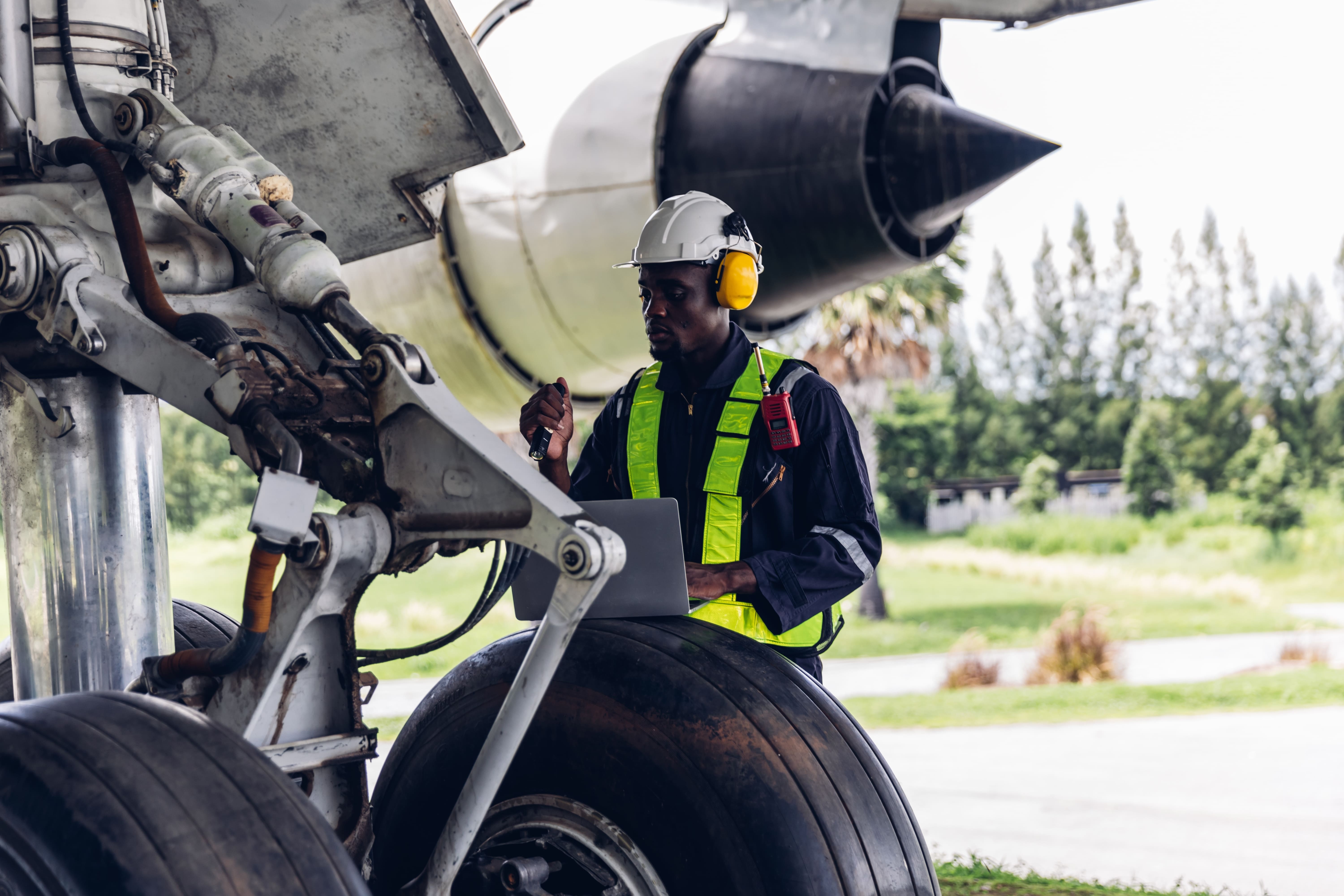 An aviation professional inspecting an aircraft with a laptop in hand